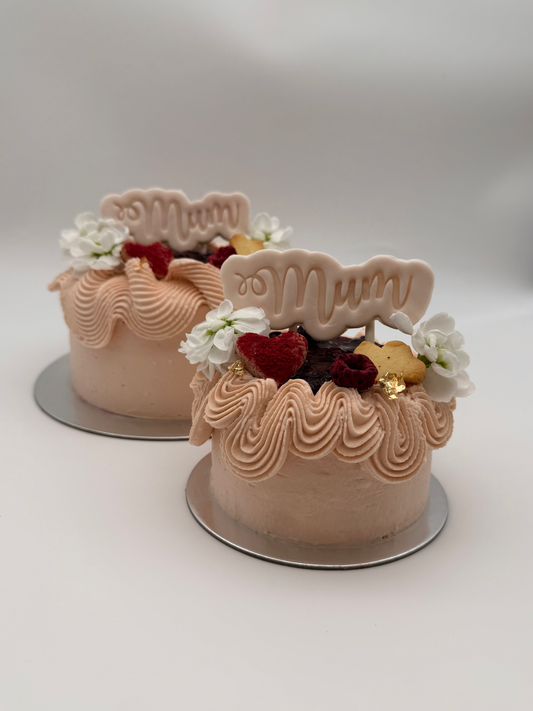Two small cakes with 'Mum' decoration on a white background