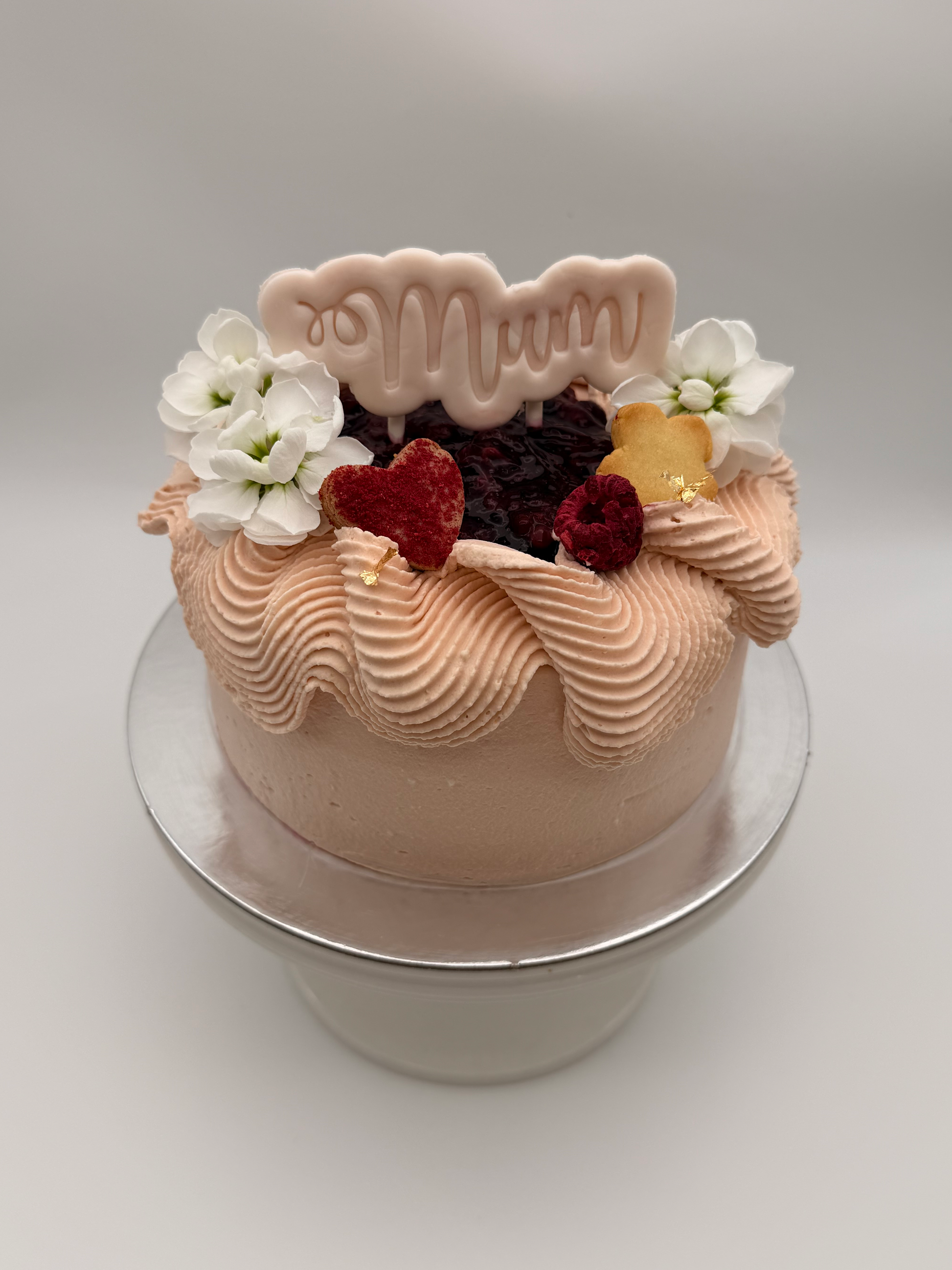 Small cake with 'Mum' decoration on a white background